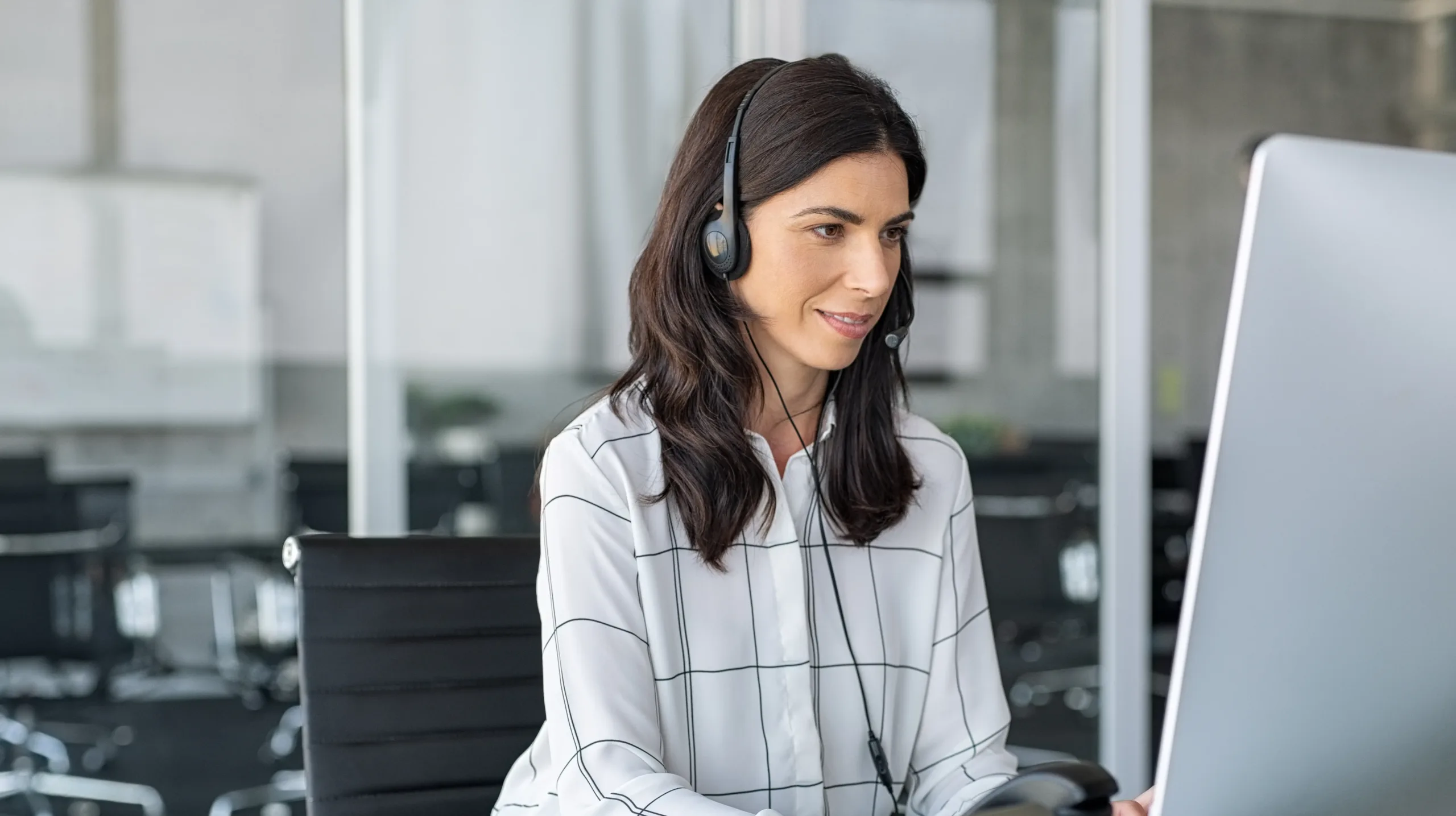 Answering service receptionist with headset sitting at computer.